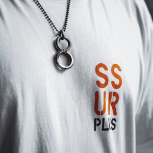 Close-up of a stylish necklace with number eight design worn over a graphic white t-shirt.